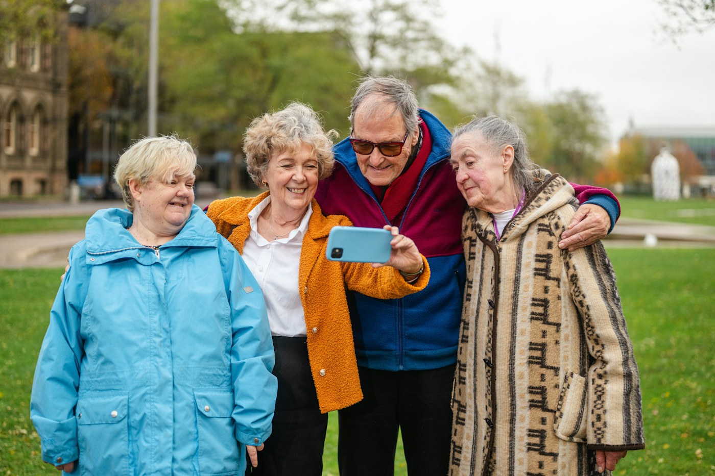 Un grupo de personas mayores sonriendo al tomarse una fotografía juntas al aire libre.